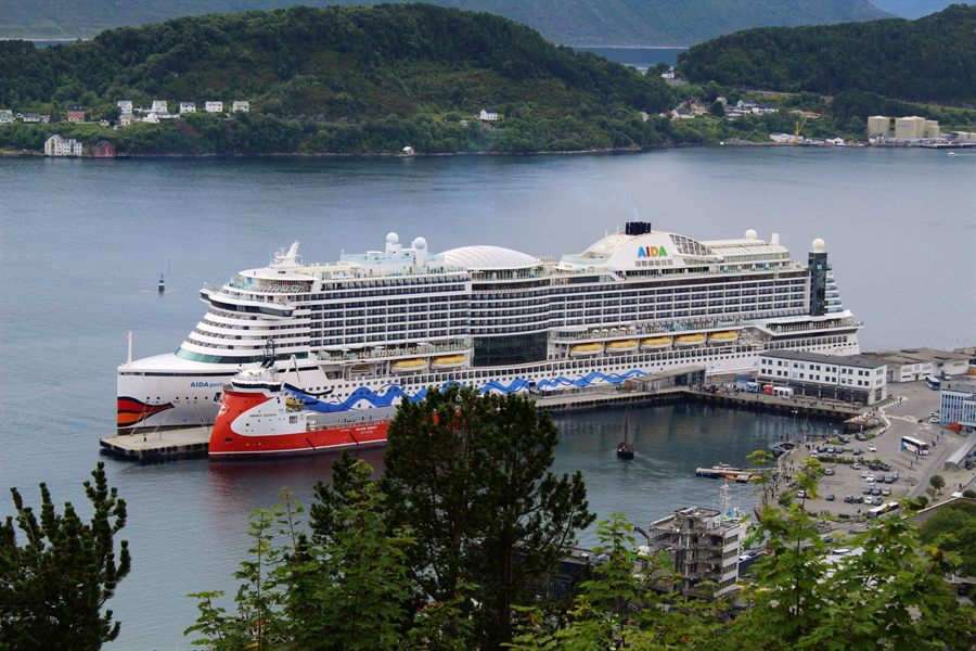 Large cruise ship at a quay in Bergen harbor with green hills behind