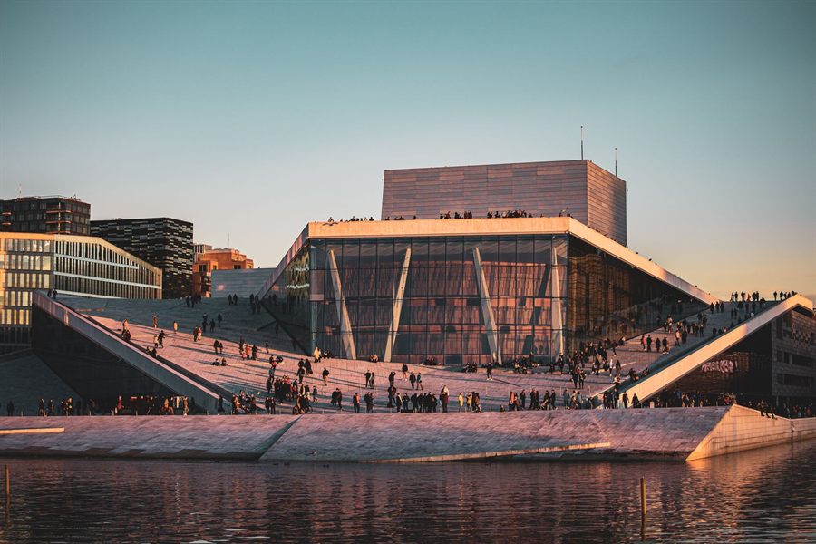People walking on the sloping roof of the Oslo Opera House at sunset