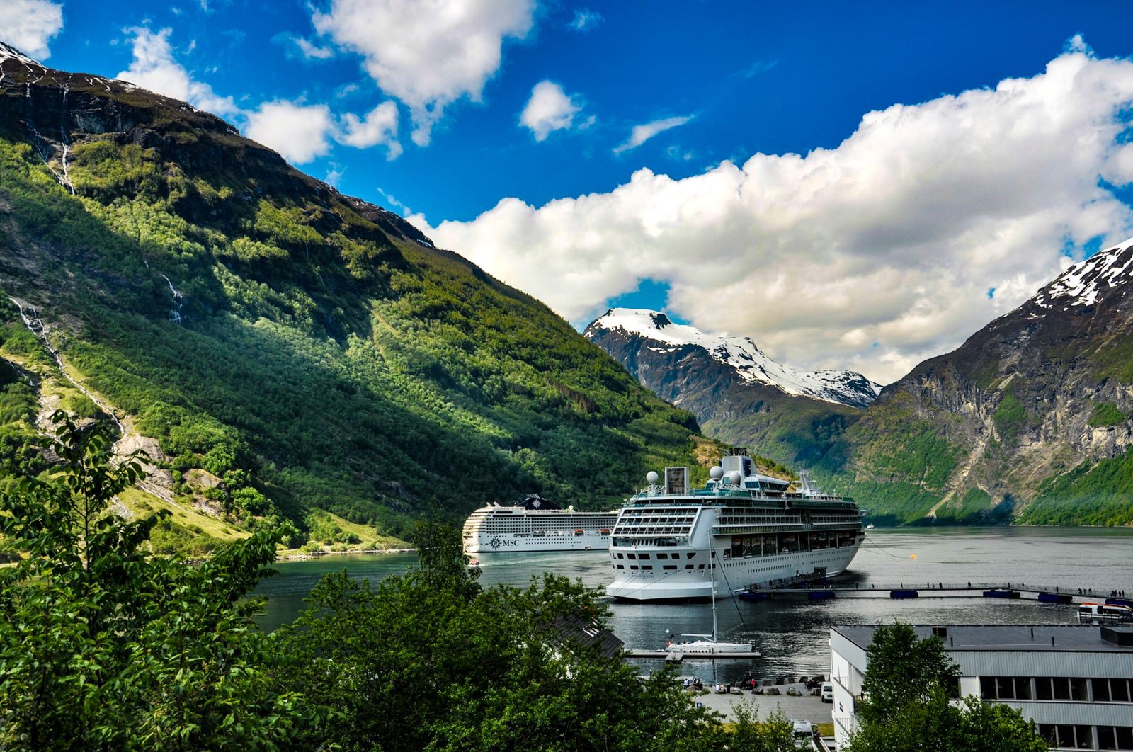 Cruise ship anchored in Geirangerfjord below steep green mountains in Norway